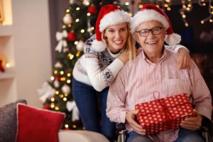 young woman wearing red Santa hat leaning in behind senior man wearing Santa hat for Christmas photo