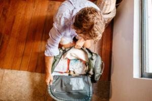 Male packing for a trip, puts clothes in a duffel bag