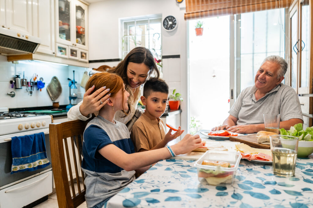 Mother embracing children during breakfast at home